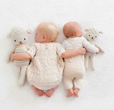 two baby babies laying next to each other on a white blanket with teddy bears in their arms