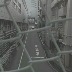 a city street with buildings and signs on the road behind a chain link fence that reads, hong kong