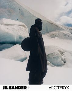 a man standing in the snow with his back to the camera and wearing a black coat