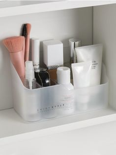 an organized bathroom shelf with cosmetics and personal care items in plastic containers on the shelves