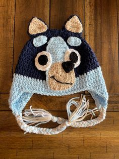 a crocheted bear hat on top of a wooden floor next to a string