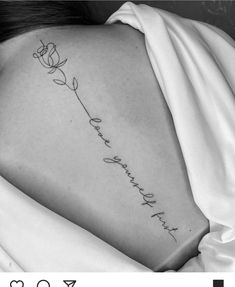 a black and white photo of a woman's back with a rose tattoo on it