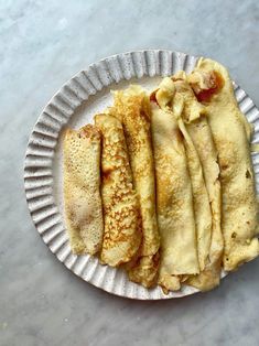 some food is on a paper plate and it looks like pancakes or crepes