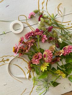 some flowers are laying on the floor next to a pair of scissors and a cup