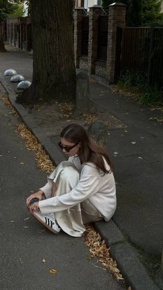 a woman sitting on the ground next to a tree