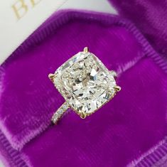 a diamond ring sitting on top of a purple velvet bag