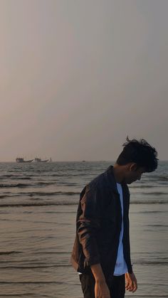 a man standing on top of a beach next to the ocean