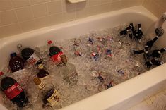 a bath tub filled with lots of bottles and glasses next to a sink full of ice