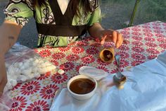 a woman sitting at a table with food on it and a cup of coffee in front of her