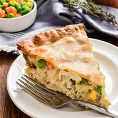 a slice of chicken pot pie on a white plate with a fork next to it