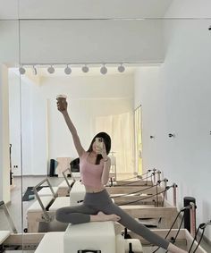 a woman sitting on top of a white bench in front of a mirror with her arms up