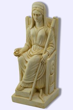 a statue of a woman sitting in a chair with a bowl on her lap and holding a staff