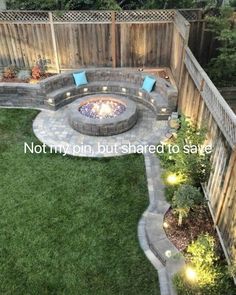 an outdoor fire pit in the middle of a yard with grass and lights around it