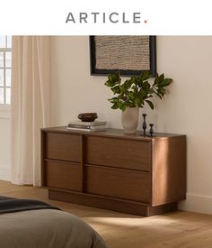 a wooden dresser sitting next to a bed with a plant on it's top