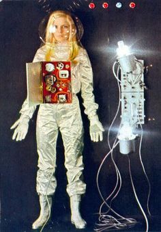 the doll is wearing an astronaut suit and holding a box with buttons on it's chest