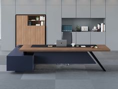 an office desk with a laptop on it in front of a bookcase and shelves