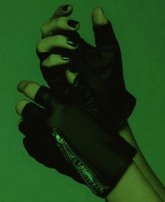 a woman's hand wearing black gloves and green nail polish holding onto her wrist