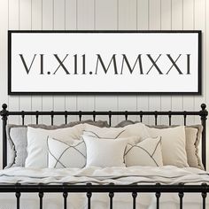 a bed with pillows and blankets underneath a large framed sign that reads, vix 11 mm xxii