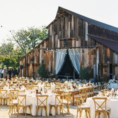 a barn with tables and chairs set up for an outdoor wedding reception in front of it