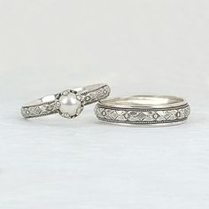 two wedding rings with diamonds and pearls on the top one is white gold, the other is silver