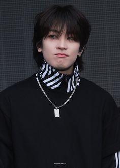 a young man wearing a black and white shirt with a zebra print scarf around his neck