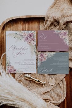 the wedding stationery is laid out on a wooden tray