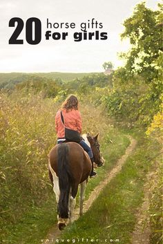 a woman riding on the back of a brown and white horse down a dirt road