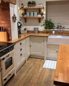 a kitchen with an oven, sink and wooden counter tops on the floor next to a brick wall