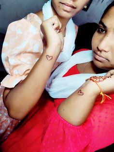 two women with tattoos on their arms posing for the camera