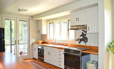 an empty kitchen with white cabinets and wood counter tops, is pictured in this image