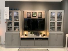 a living room with gray furniture and pictures on the wall above it's entertainment center