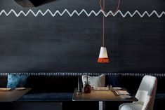 a table with two chairs and a lamp hanging from it's side in front of a black wall