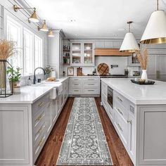 a large kitchen with white cabinets and wooden floors, along with a blue runner rug on the floor