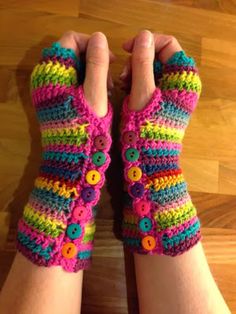 a woman's hands wearing colorful knitted fingerless gloves with buttons on them