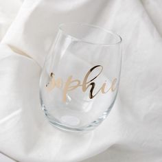 a wine glass with the word surprise written on it, sitting on a white cloth