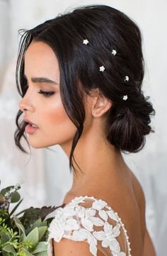 a woman in a wedding dress holding a bouquet with flowers on her head and looking off to the side