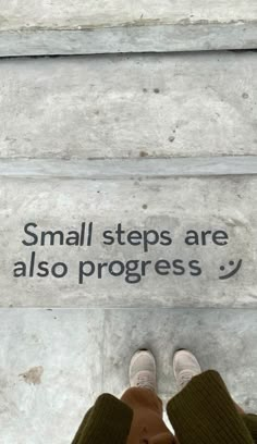 a person standing in front of a sign that says small steps are also progress '