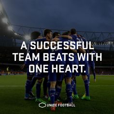 a group of soccer players huddle together on the field in front of an empty stadium