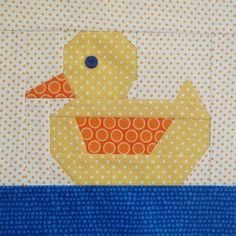 a yellow ducky is sitting in the middle of a blue and white quilted piece