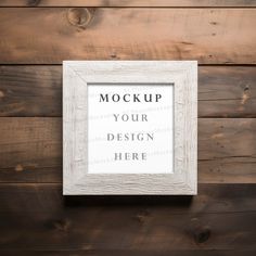 a white frame hanging on a wooden wall mockup for your design here sign or poster