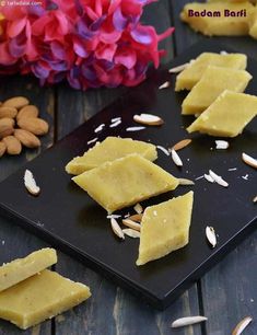 some kind of food that is on a black plate with almonds and flowers in the background