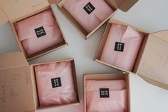 four boxes with pink sheets in them sitting on a table