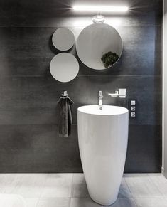 a white sink sitting under three mirrors in a bathroom