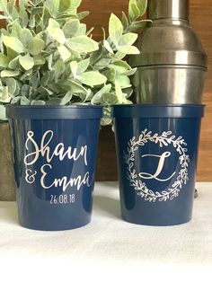 two cups with names on them sitting next to a potted plant