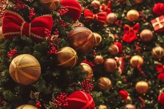 a christmas tree with red and gold ornaments on it's sides, surrounded by other holiday decorations