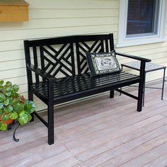 a black bench sitting on top of a wooden deck next to a potted plant