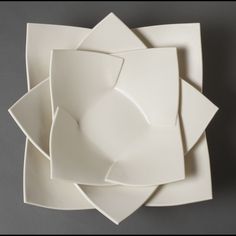 four white plates stacked on top of each other in the shape of an origami flower