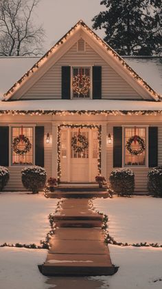 a house covered in christmas lights with wreaths on the front door and windows, all lit up