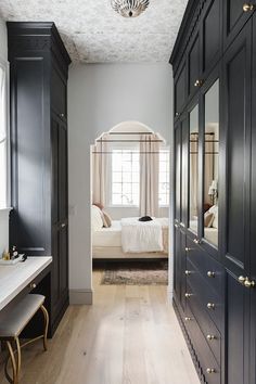 a white bed sitting in a bedroom next to black cabinets