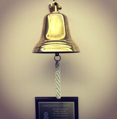 a bell hanging from the side of a wall next to a plaque that reads congratulations